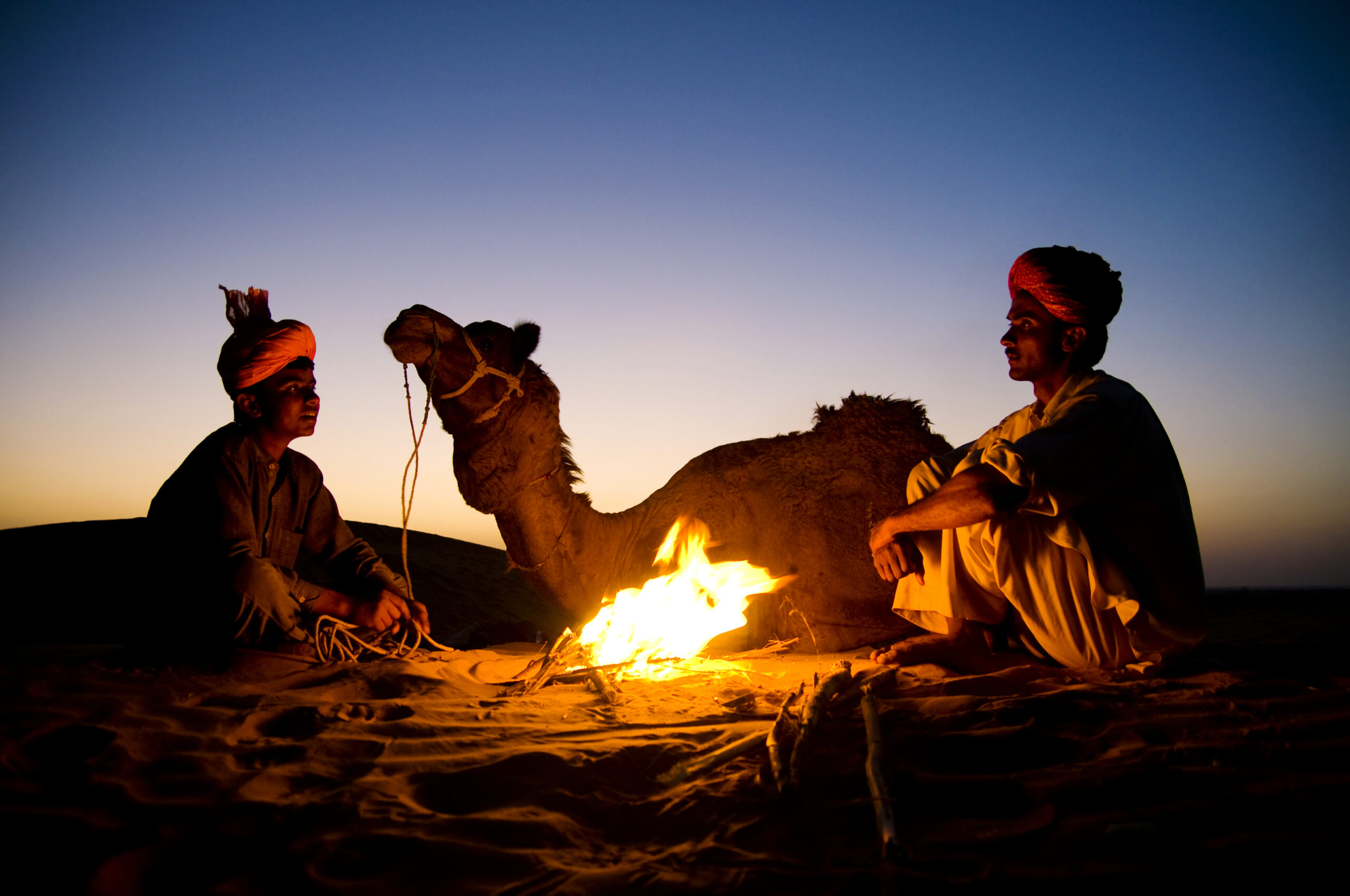 indian-men-resting-by-bonfire-with-their-camel-scaled.jpg