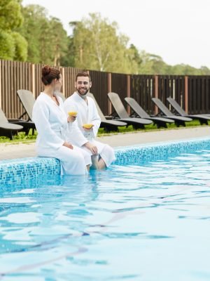 Restful young couple with drinks spending vacation in luxurious spa resort